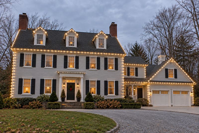 Gray colonial at twilight with roofline and corners lit